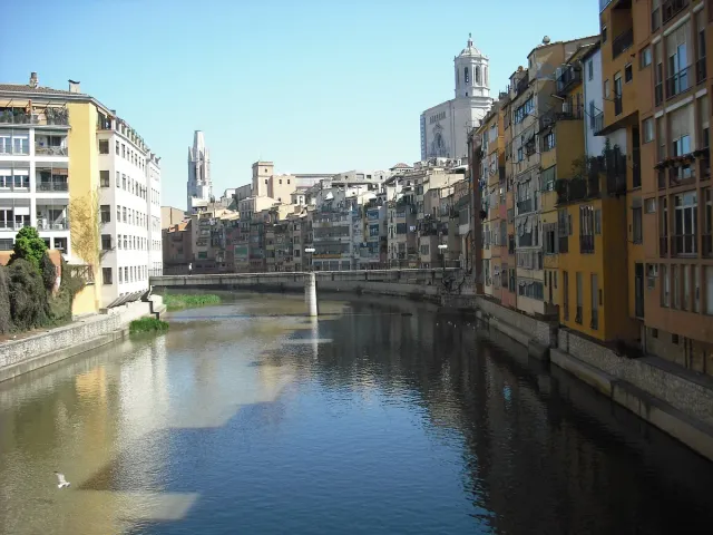 Colourful houses reflected in a narrow river with a cathedral tower behind