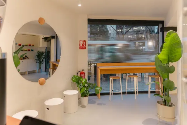 A bright space with a round mirror, a wooden counter facing the window and stools