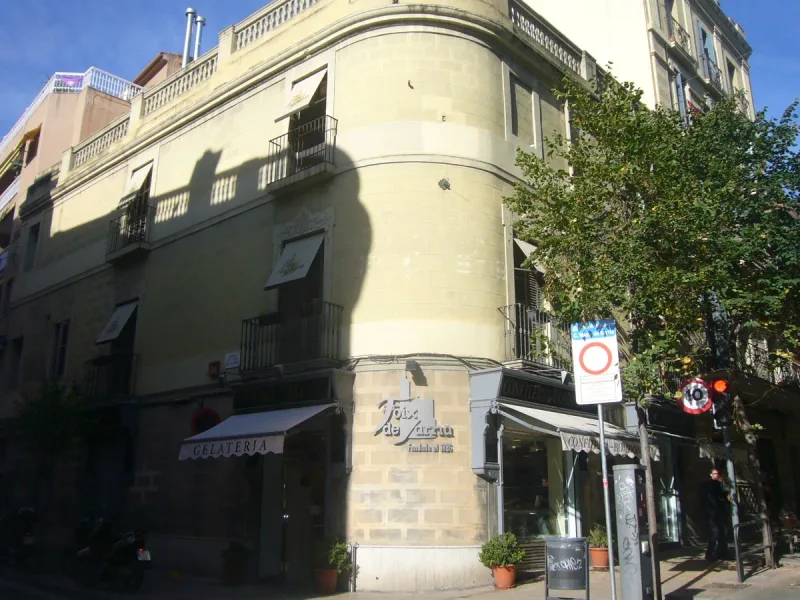 Neighbourhood street corner with yellow facades, small shops and a road sign