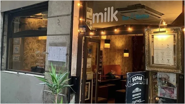 A lit entrance in the evening with a string of lights, a chalkboard and a menu in a gilded frame