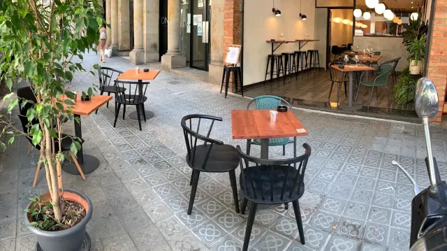 Orange tables and black chairs on patterned tiles, under passage arches