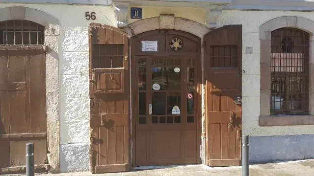 A brown arched wooden door at number 56, with stickers and closed shutters beside it