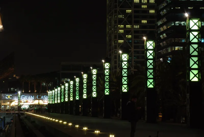 Night promenade with green lit columns and an illuminated casino sign