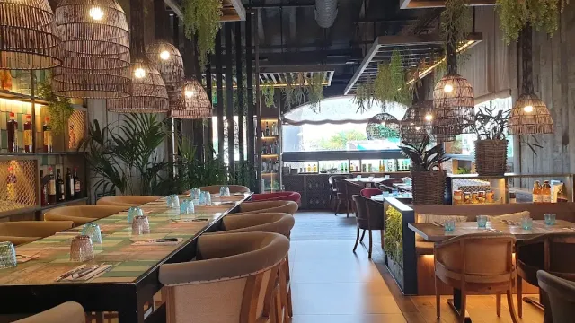 A hall with large straw lamps, hanging greenery and long tables beside a counter