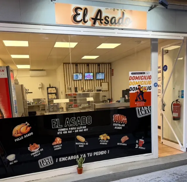 A takeaway food shop front with a wide glass window and illustrated menu decals