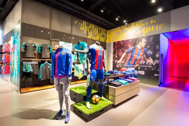 A shop interior with mannequins in football kits, shelves of shirts and a player poster on the wall