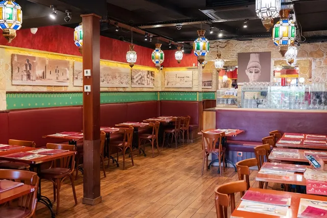 A dining hall with red banquettes, colourful oriental lanterns and pictures on a stone wall