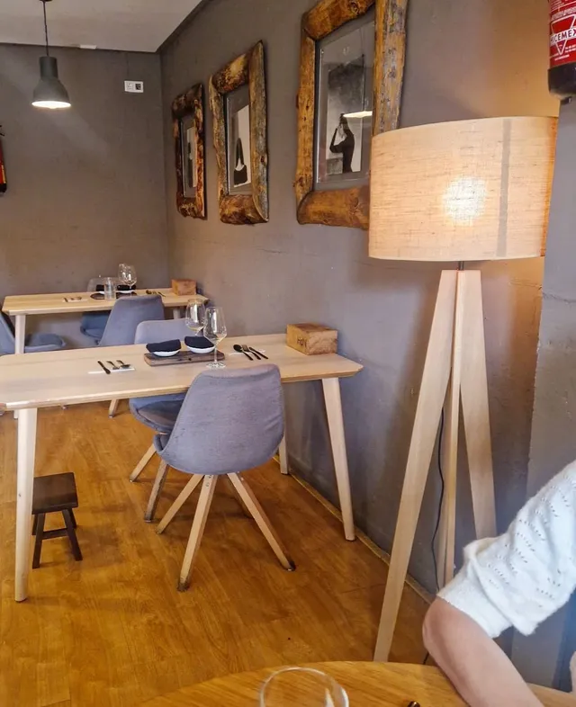 Light wooden tables with upholstered chairs, a floor lamp and mirrors in raw wood frames